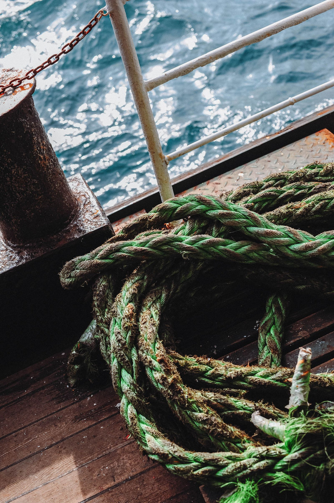 Coiled green climbing rope resting on a wooden deck, the same coiled shape used to make a rope bowl