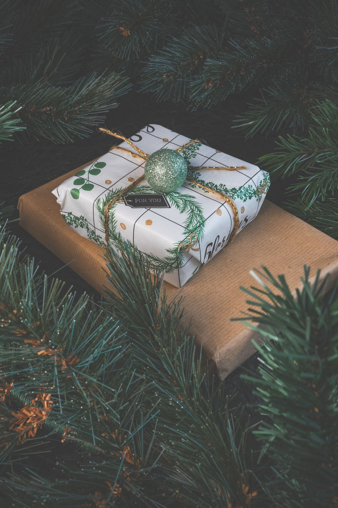 Small wrapped gifts sitting among conifer branches