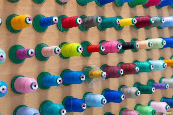 Wall of colourful thread spools arranged in neat rows in a workshop
