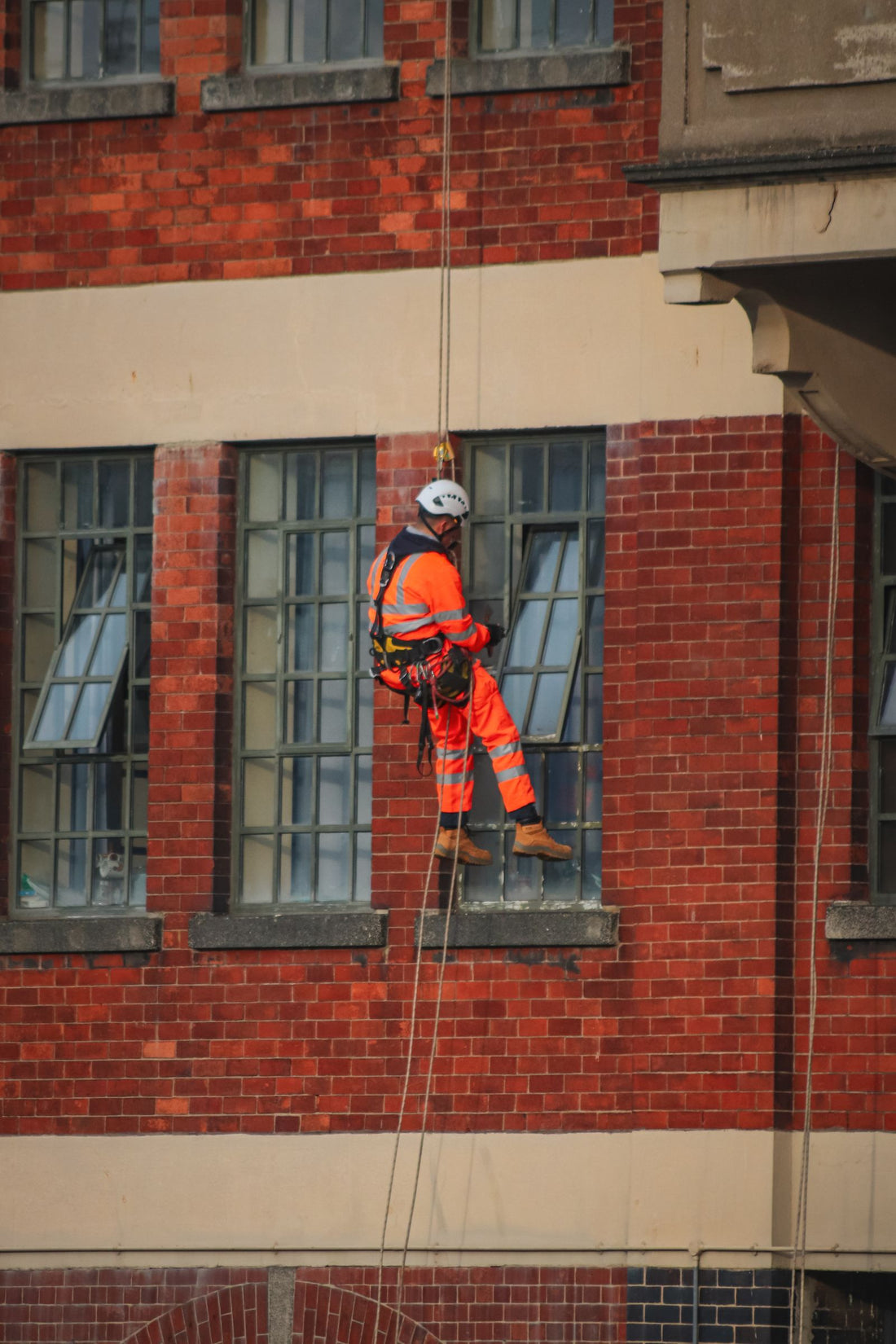 A rope access technician working on the side of a building suspended on ropes