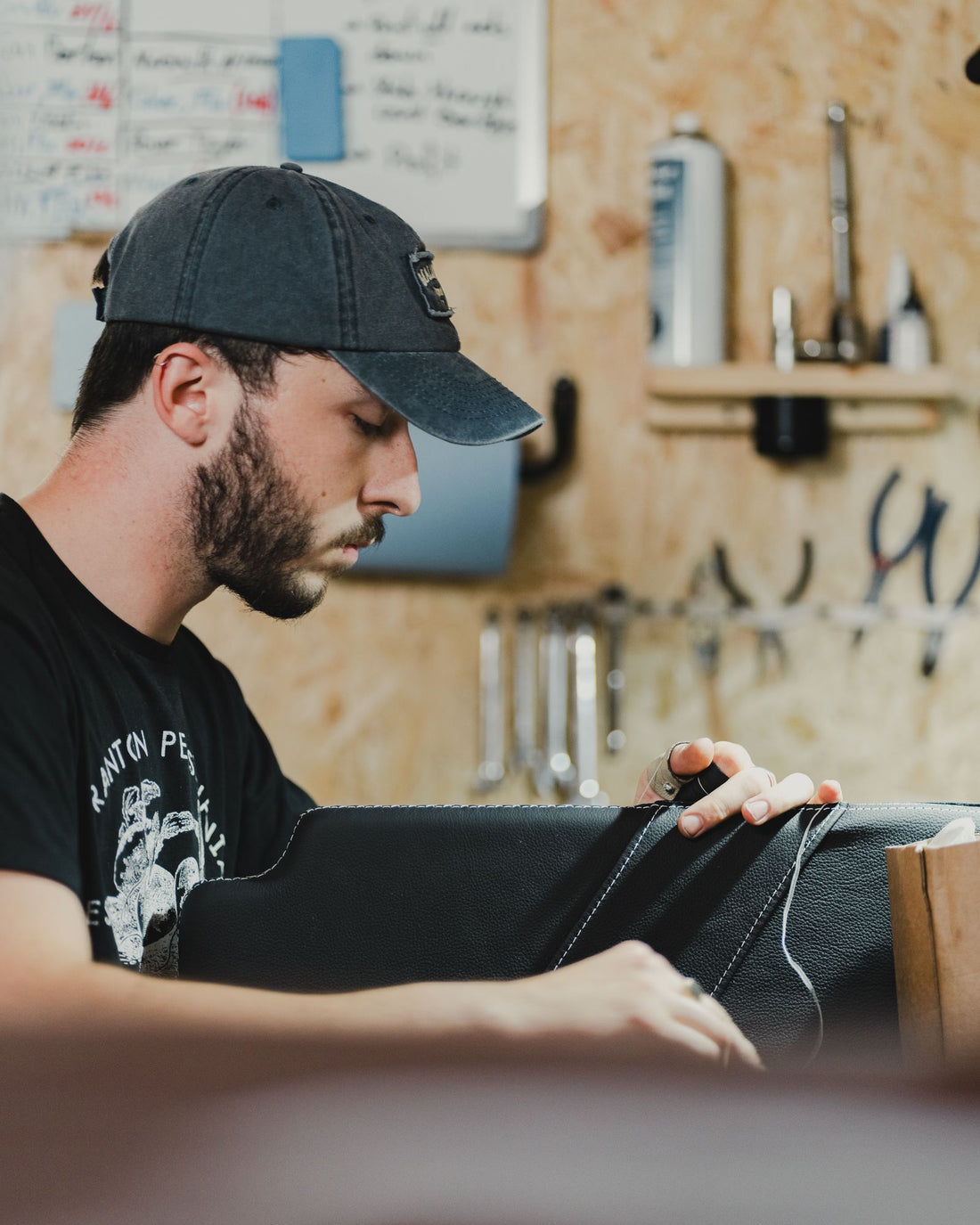 A maker working at a cluttered workbench, hands busy with tools and material
