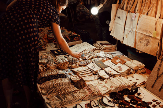 A customer choosing handmade goods from a table at a local market stall.