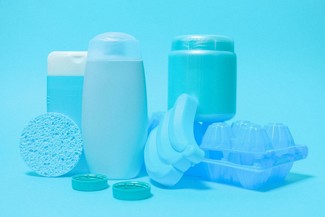Assorted empty HDPE plastic bottles, containers and lids laid out on a blue background