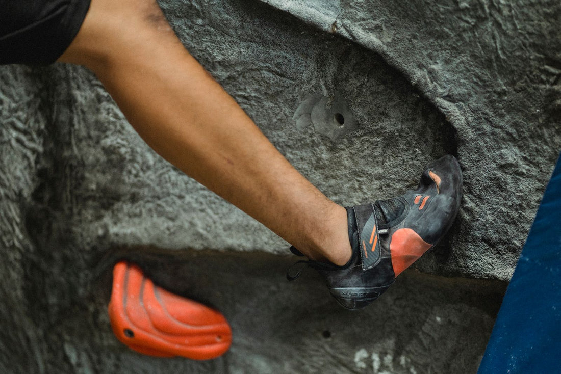 A climber bouldering on a wall of colourful holds in an indoor climbing centre
