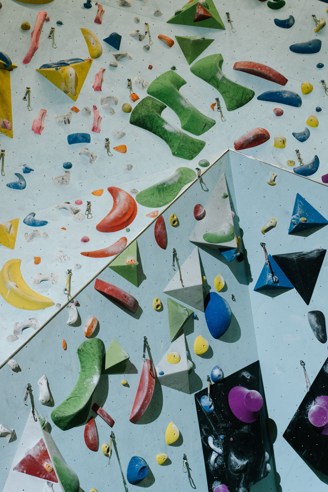 An indoor climbing wall with colourful holds and ropes running down the face