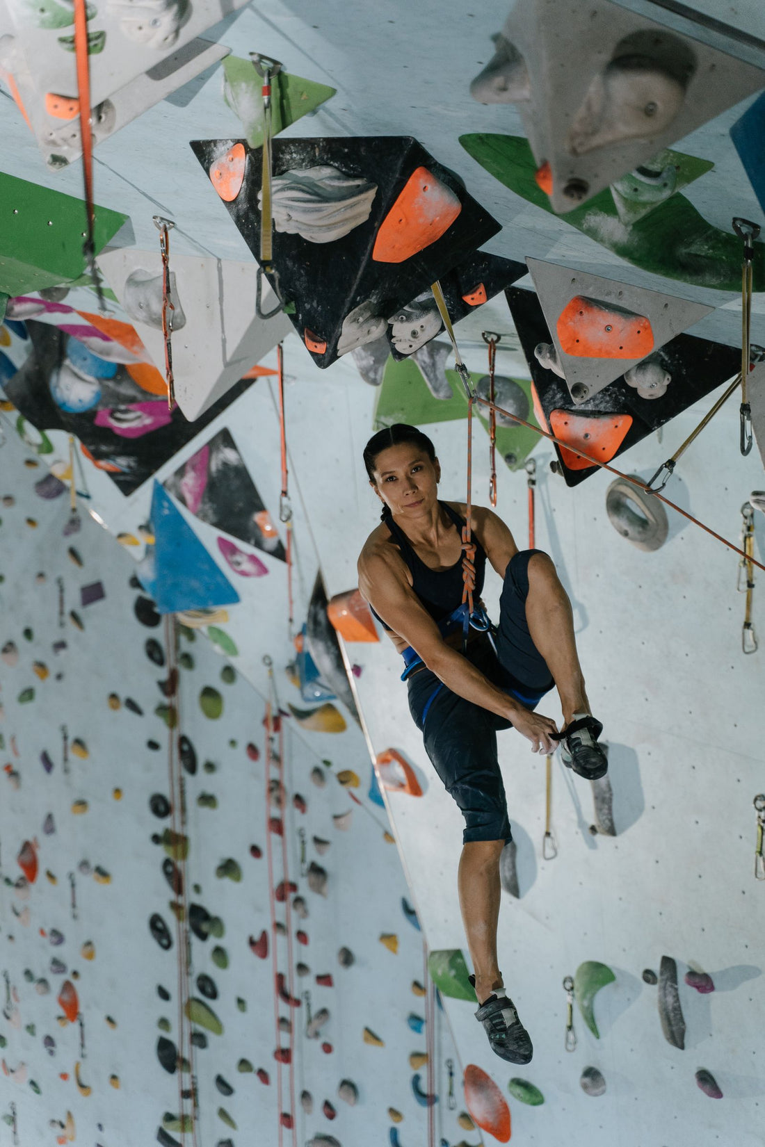 A climber hanging on the rope beside an indoor climbing wall
