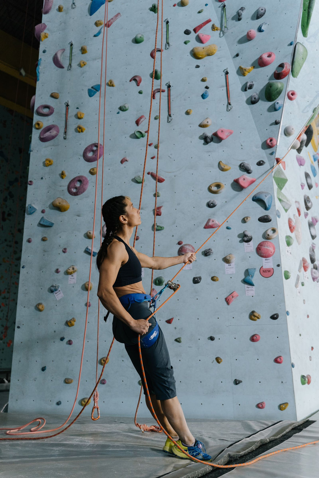 Climber at an indoor climbing wall holding a climbing rope